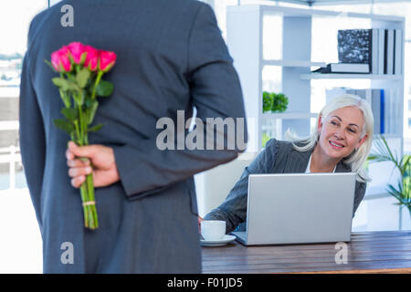 Geschäftsmann versteckt Blumen hinter Rücken für Kollegen Stockfoto