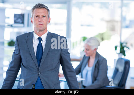 Blick in die Kamera mit seinen Kollegen hinter ihm Geschäftsmann Stockfoto