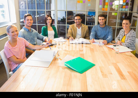 Lächelnde Geschäftsleute, die in die Kamera während eines Meetings Stockfoto