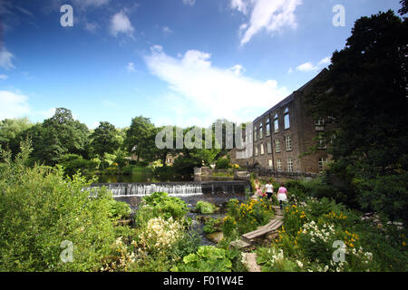 Menschen überqueren die öffentliche Fußgängerbrücke über den Derwent Bamford Mill und Wehr in der Peak District National Park, England Stockfoto