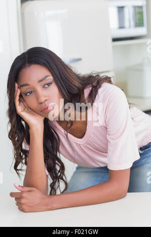 Traurige Frau denkt an der Theke Stockfoto