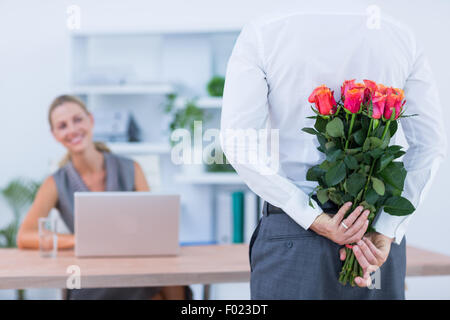 Geschäftsmann versteckt Blumen hinter Rücken für Kollegen Stockfoto