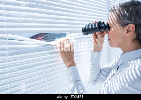 Geschäftsfrau, Blick durch ein Fernglas im Büro Stockfoto