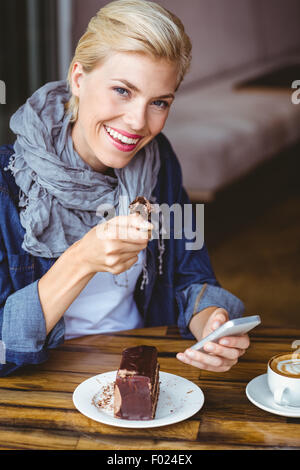 Lächelnde Blondine ein Stück Schokoladenkuchen Stockfoto