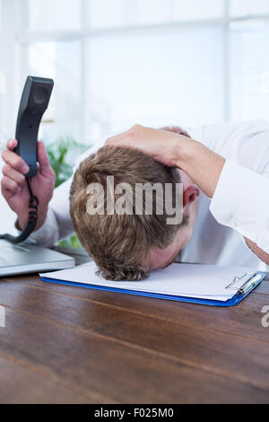 Gereizte Geschäftsmann hält ein Festnetz Telefon Stockfoto