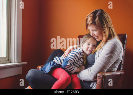 Mutter und Tochter zusammen in einem Sessel sitzend Stockfoto