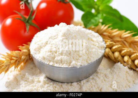 Schüssel mit fein gemahlenem Mehl, Ähren und frische Tomaten - Stillleben Stockfoto