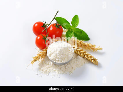 Schüssel mit fein gemahlenem Mehl, Ähren und frische Tomaten - Stillleben Stockfoto