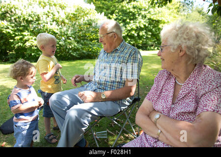 Großeltern, alte Rentner draußen in der Sonne, mit jüngeren Generationen ihrer Familie, England, UK Stockfoto