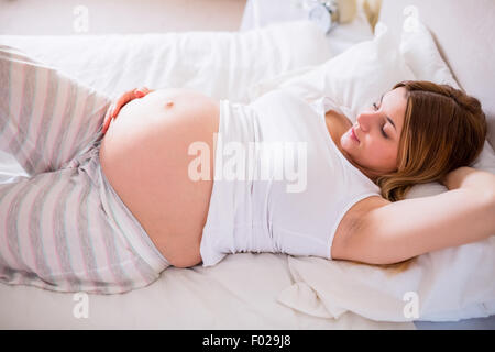 Glücklich schwanger Frau auf Bett liegend Stockfoto