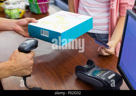 Lächelnde Frau an Kasse bezahlen mit Kreditkarte und Scan eines Produkts Stockfoto