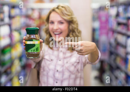 Glücklich lächelnd blonde Frau, die ein Produkt Stockfoto