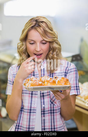 Lächelnde blonde Frau mit einem Gebäck Stockfoto