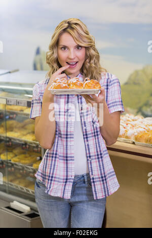 Porträt einer lächelnden blonde Frau mit einem Gebäck Stockfoto