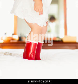 Nahaufnahme eines Mädchens in roten Stiefeln auf einem Bett springen Stockfoto