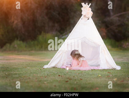 Mädchen sitzt in einem Wigwam und blickt in eine Laterne, Kalifornien, USA Stockfoto