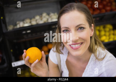 Lächelnde hübsche blonde Frau kaufen Orangen Stockfoto