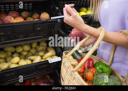 Lächelnde Frau, die eine Frucht in den Gang Stockfoto