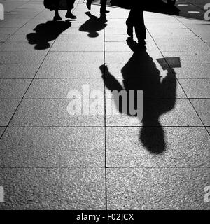 Schatten und Silhouetten von Menschen gehen auf der Straße in der Stadt Stockfoto