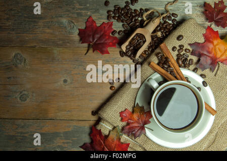 Heißer Kaffee in der Tasse auf einem hölzernen Hintergrund mit Herbst Blätter Stockfoto