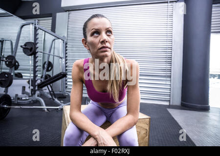 Schwere muskulöse Frau sitzen auf einer Holzkiste Stockfoto