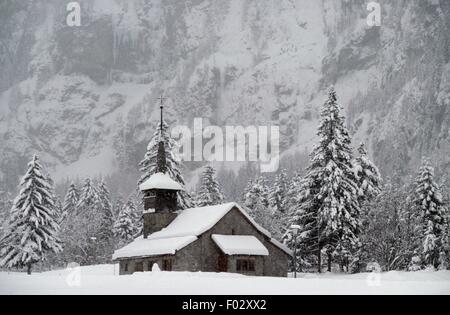 Die katholische Kirche von Kandersteg, umgeben von schneebedeckten Nadelbäume, Kanton Bern, Schweiz. Stockfoto