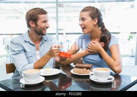 Junge glückliche Paar essen Kuchen und Mann, indem er ihr einen ring Stockfoto
