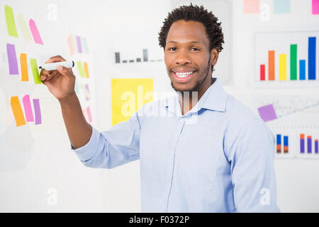 Lächelnde Jungunternehmer auf Notizzettel schreiben Stockfoto