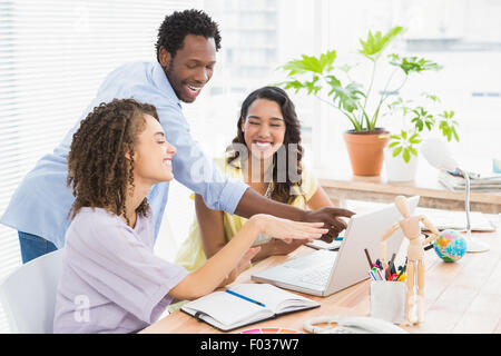 Glückliche Mitarbeiter mit Laptop am Schreibtisch Stockfoto