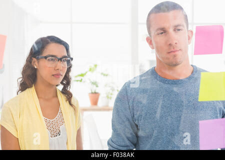 Konzentrierte sich Kollegen lesen Haftnotizen Stockfoto