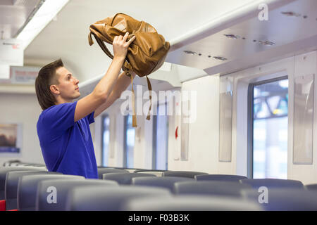 Kaukasischen Jüngling, Gepäck auf dem obersten Regal auf Flugzeuge Stockfoto