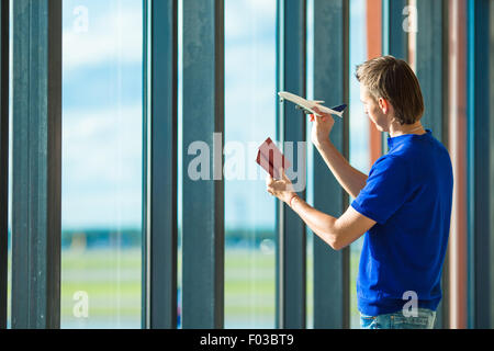 Junger Mann mit Pässen, Bordkarte und Flugmodell Spielzeug am Flughafen Stockfoto