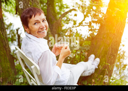 Entspannte senior Frau eine Pause mit Tee in ihrem Garten Stockfoto