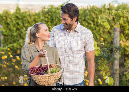 Zwei junge glücklich Winzer hält einen Korb mit Trauben Stockfoto