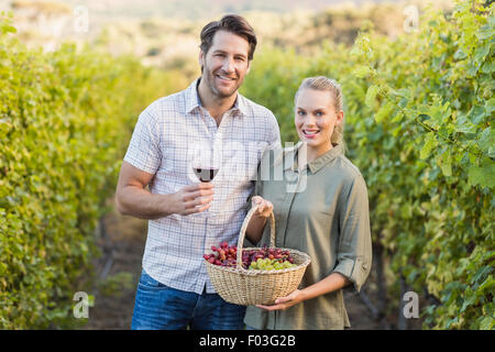 Zwei junge glücklich Winzer hält einen Korb mit Trauben und einem Glas Wein Stockfoto