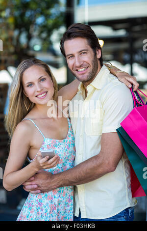 Lächelnde paar umarmen und halten smartphone Stockfoto