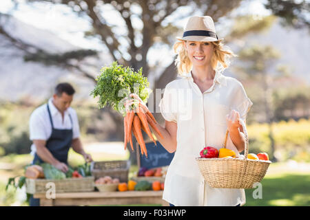 Blonde Frau hält eine Reihe von Karotten Stockfoto