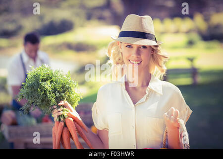 Blonde Frau hält eine Reihe von Karotten Stockfoto