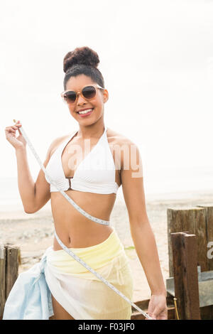 Hübsche Frau im Bikini, die ihre Taille messen Stockfoto