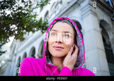 Porträt einer Frau mit einer rosa Jacke setzen ihre Kopfhörer Stockfoto