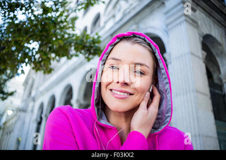 Porträt einer Frau mit einer rosa Jacke setzen ihre Kopfhörer Stockfoto