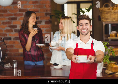 Hübscher Kellner übergeben eine Tasse Kaffee Stockfoto