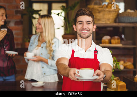 Hübscher Kellner übergeben eine Tasse Kaffee Stockfoto