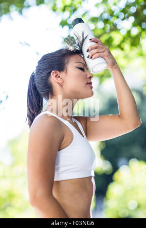 Müde athletische Frau Kühlung Stirn mit Wasserflasche Stockfoto