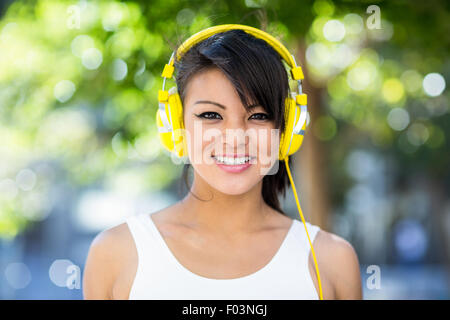 Porträt von lächelnden athletische Frau trägt gelbe Kopfhörer Stockfoto