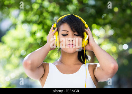 Sportliche Frau trägt gelbe Kopfhörer und genießen Sie Musik mit geschlossenen Augen Stockfoto