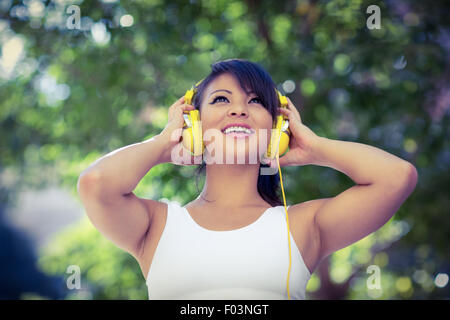 Sportliche Frau, trägt gelbe Kopfhörer und Musik genießen Stockfoto