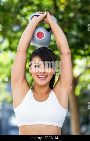 Porträt der lächelnde athletische Frau Kettlebell lifting Stockfoto