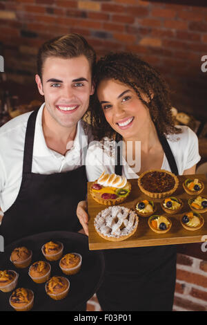 Lächelnd, Kellner und Kellnerin hält Tablett mit muffins Stockfoto