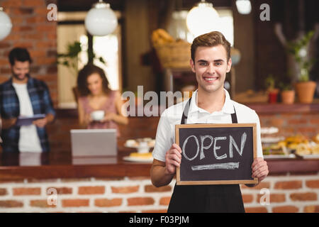 Lächelnde Barista-Holding-Tafel mit Schild "geöffnet" Stockfoto